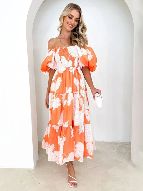 Off-the-shoulder orange dress with white floral print, puffed sleeves, and tiered skirt on model.