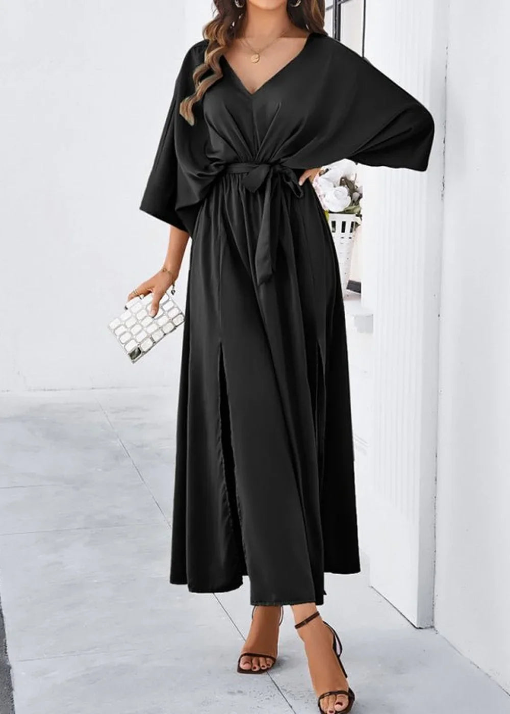 Black V-neck maxi dress with tie waist and side slits on model.