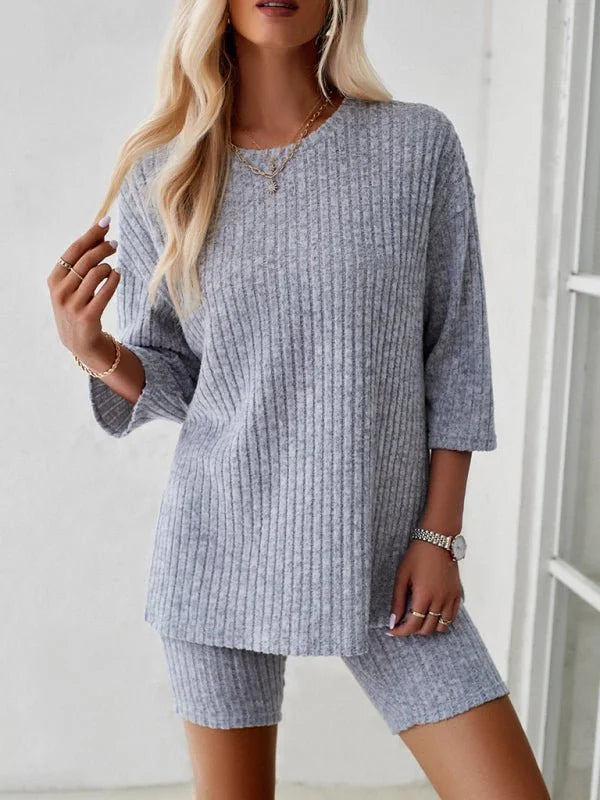 Light grey ribbed knit loungewear set on a model, showing a relaxed-fit top and biker shorts.
