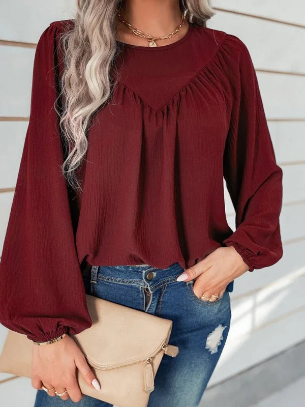 Maroon peasant blouse with billowy sleeves and a textured finish, paired with distressed denim jeans.