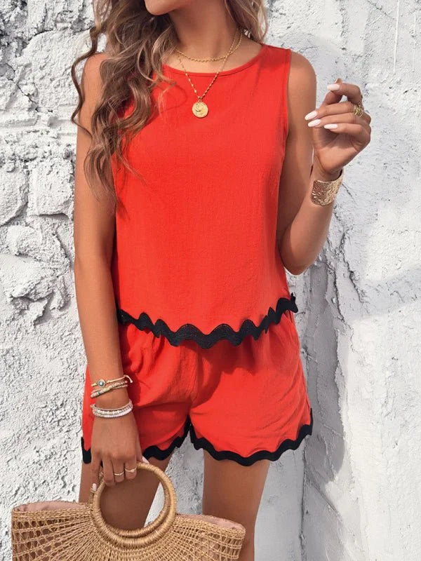 Vibrant red sleeveless top and shorts set with black scalloped trim, worn by a model with gold jewelry.