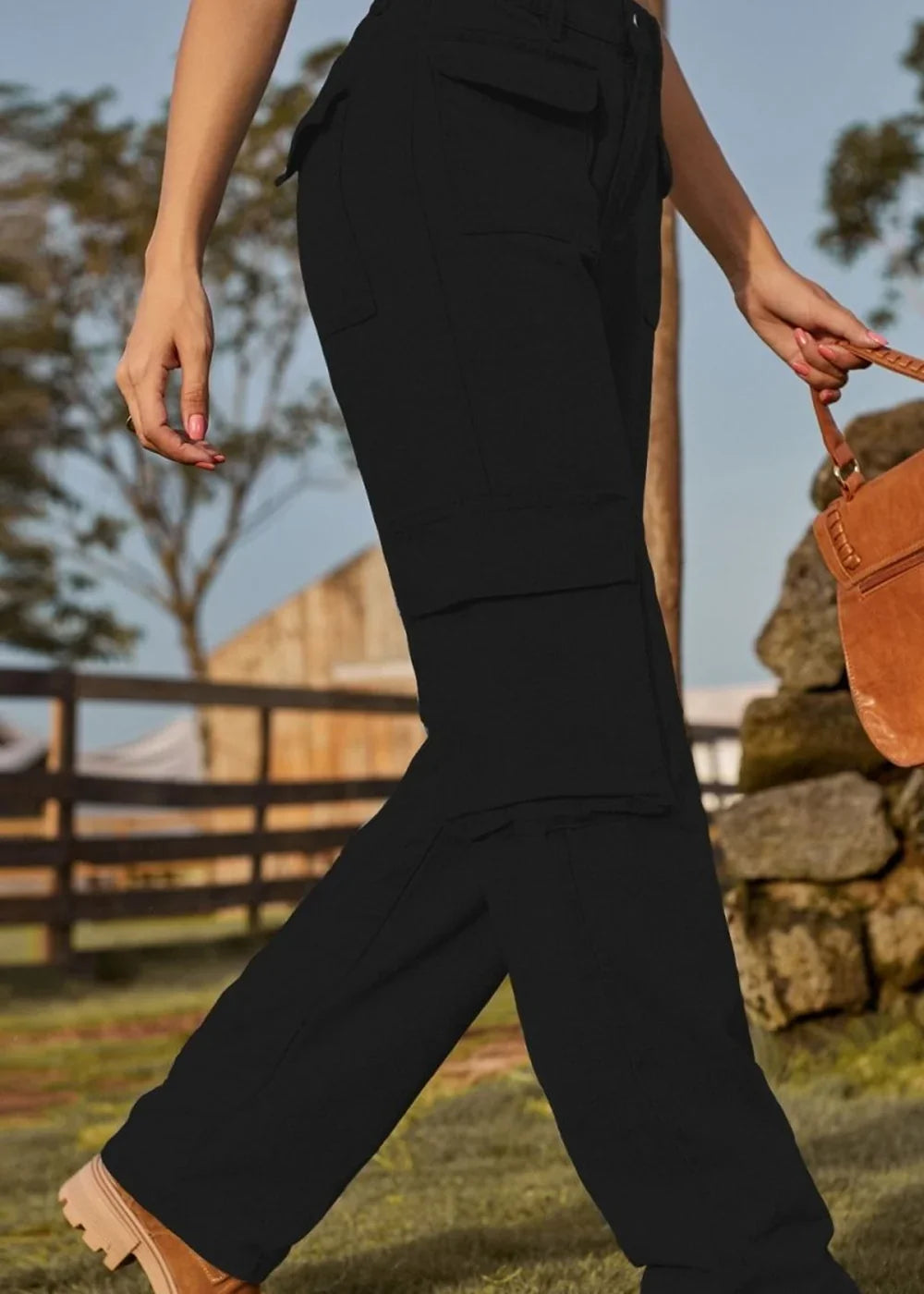 Black cargo pants with a regular fit, featuring multiple pockets and a textured fabric, shown on a model walking outdoors.