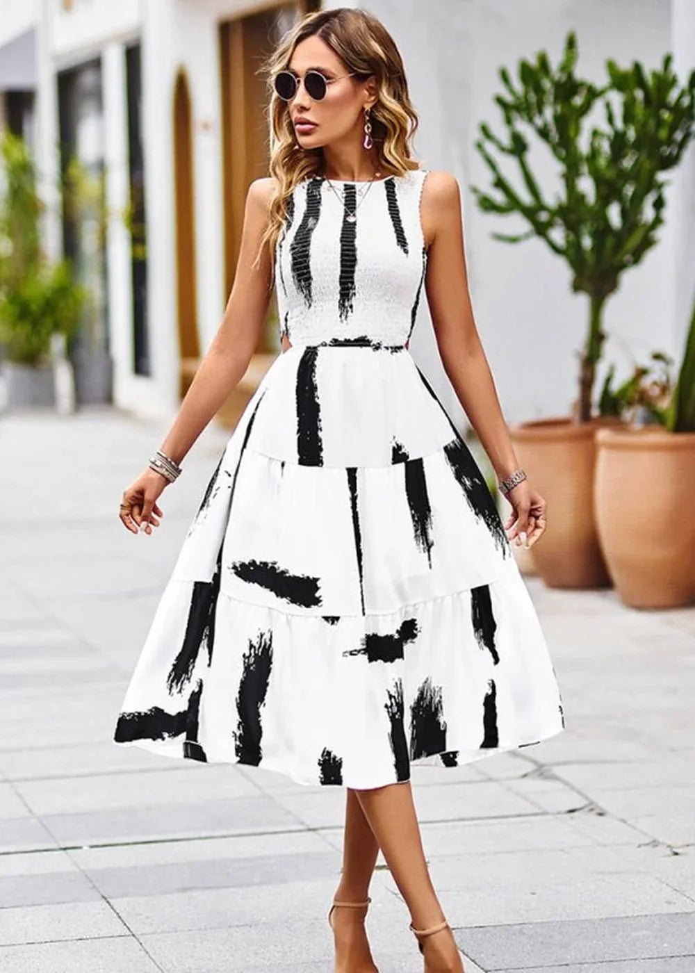 Woman in a white midi dress with black brushstroke print and tiered skirt.