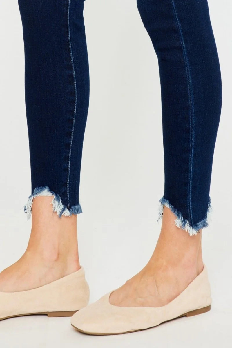 Dark wash denim jeans with frayed hems and light tan ballet flats.