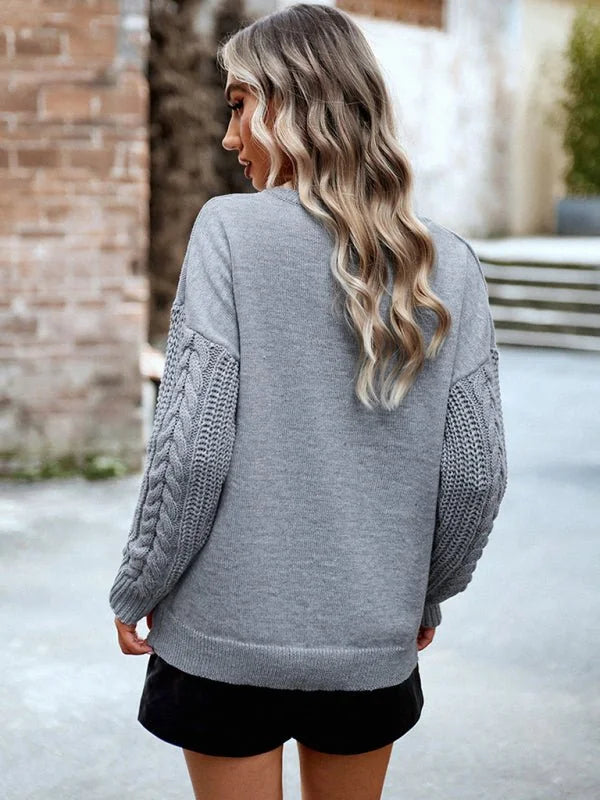Gray cable knit sweater with textured sleeves, shown from the back on a model.
