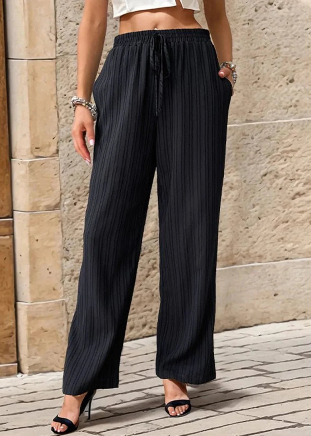 Black textured wide-leg pants with drawstring waist and pockets, shown on model.