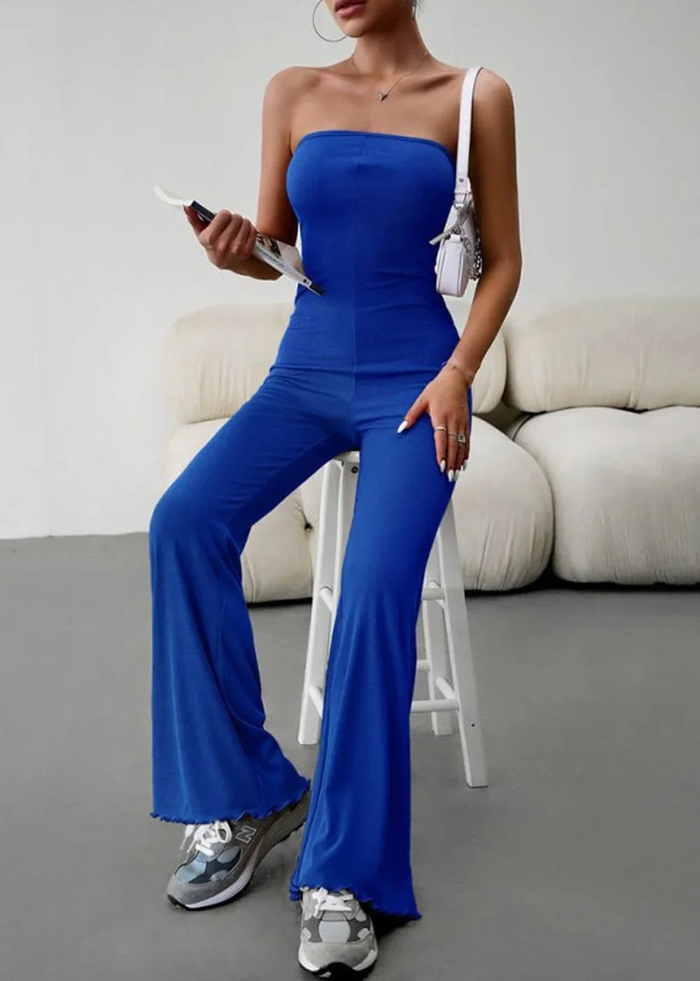 Royal blue strapless flared jumpsuit with ruffled hem, worn with sneakers.