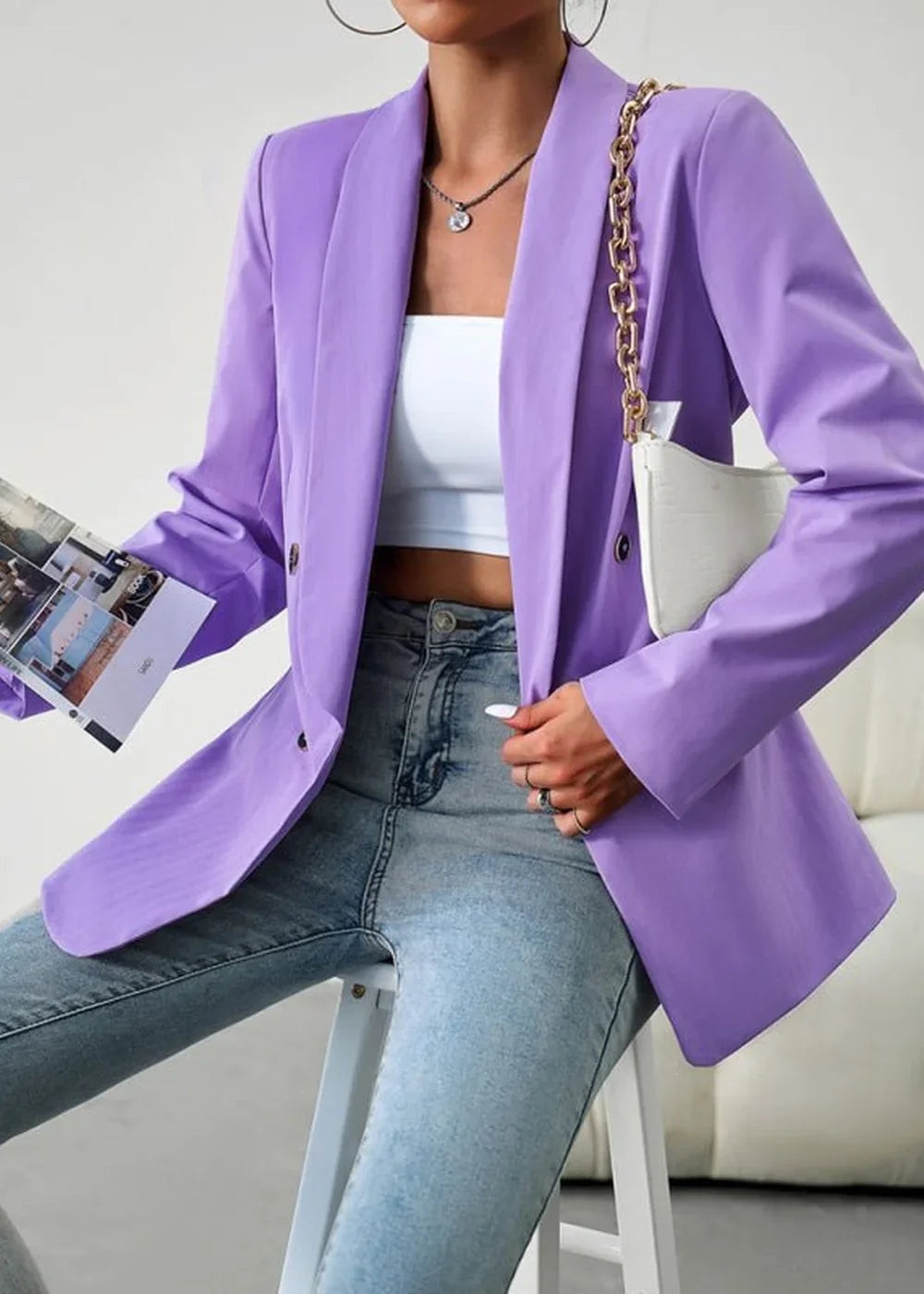 Lavender double-breasted blazer with gold chain strap handbag and light wash jeans.