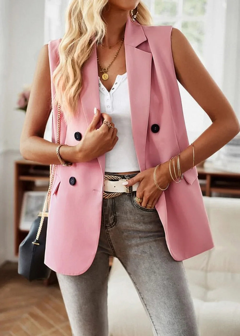 Pink sleeveless blazer with double-breasted buttons and gold jewelry on a model.