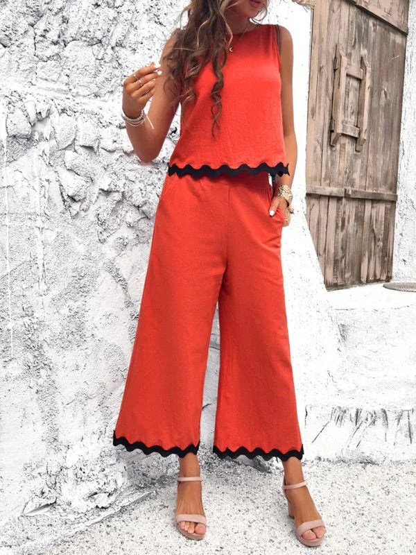 Orange wide-leg pant suit with scalloped black trim on a woman wearing pink sandals.