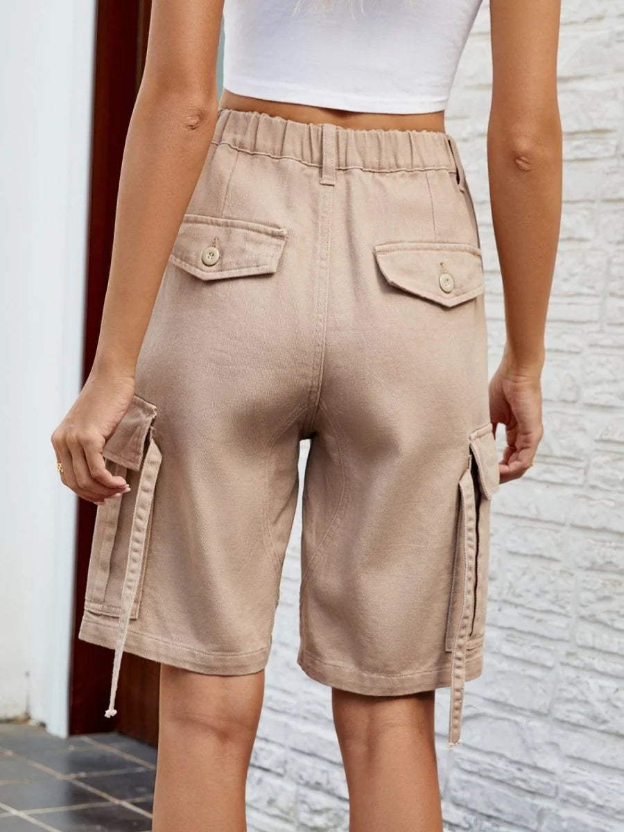 Back view of beige cargo shorts with elastic waist and button flap pockets.