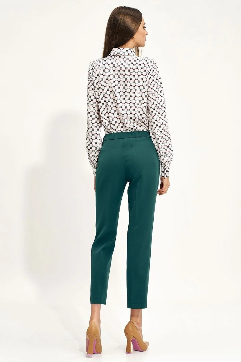 Back view of teal polyester pants with a regular fit, paired with a patterned button-up shirt and tan heels.