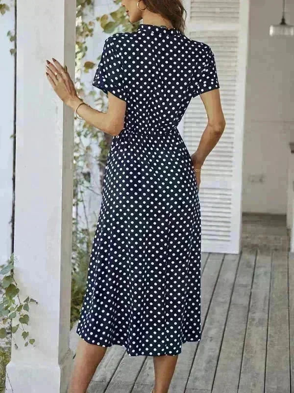 Navy blue rayon midi dress with white polka dots, featuring a cinched waist and short sleeves.