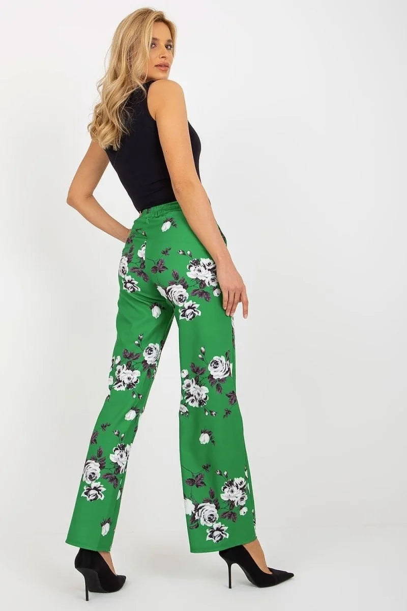 Green wide-leg pants with a white and purple floral pattern, shown on a model from the back.