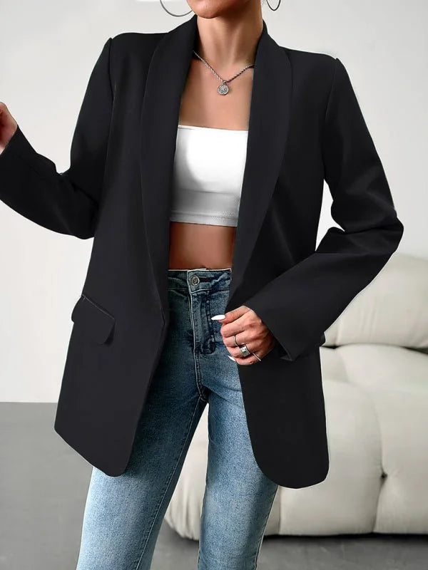 Black blazer with a sleek collar and button closure, worn over a white crop top and blue jeans.