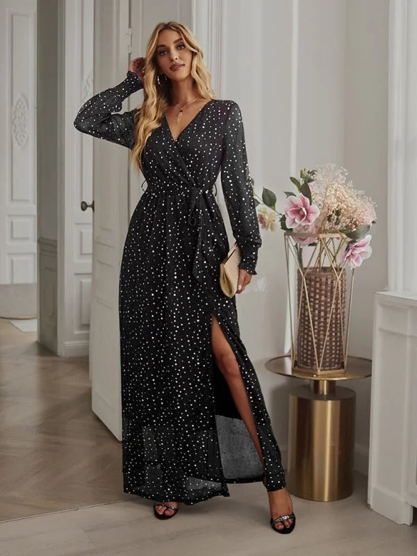 Black polka dot maxi dress with a V-neck, long sleeves, and a thigh-high slit, shown on a model.