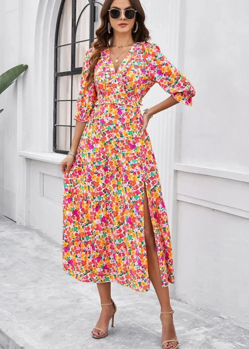 A vibrant floral print midi dress with a V-neck, ruffled trim, and a thigh-high slit.