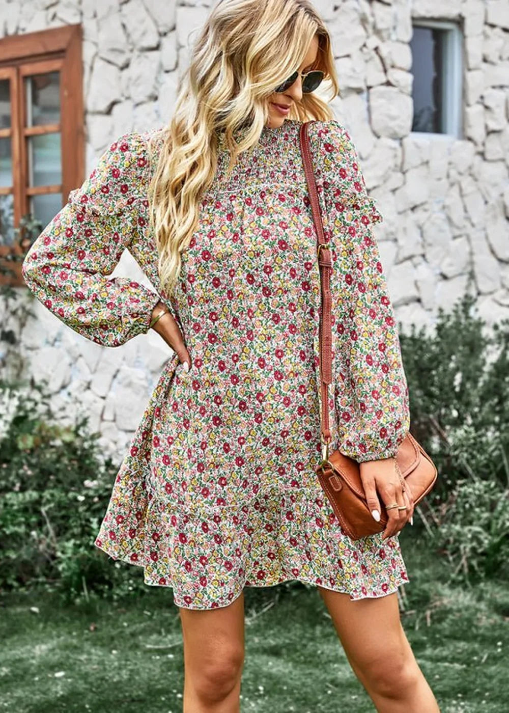 Woman in a floral print dress with smocked neckline and ruffled sleeves, carrying a brown crossbody bag.