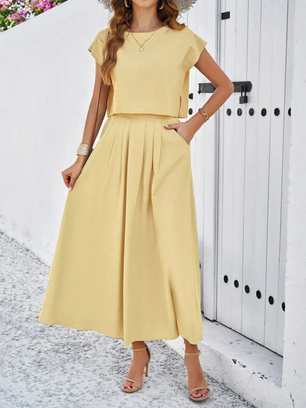 Woman in a pale yellow cropped top and pleated midi skirt, both made of textured viscose fabric.
