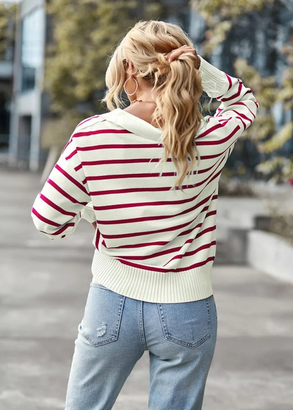 Cream sweater with red stripes and distressed denim jeans, back view.