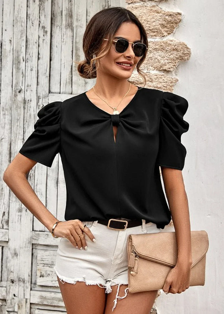 Black puffed-sleeve top with bow detail and white denim shorts on a model.