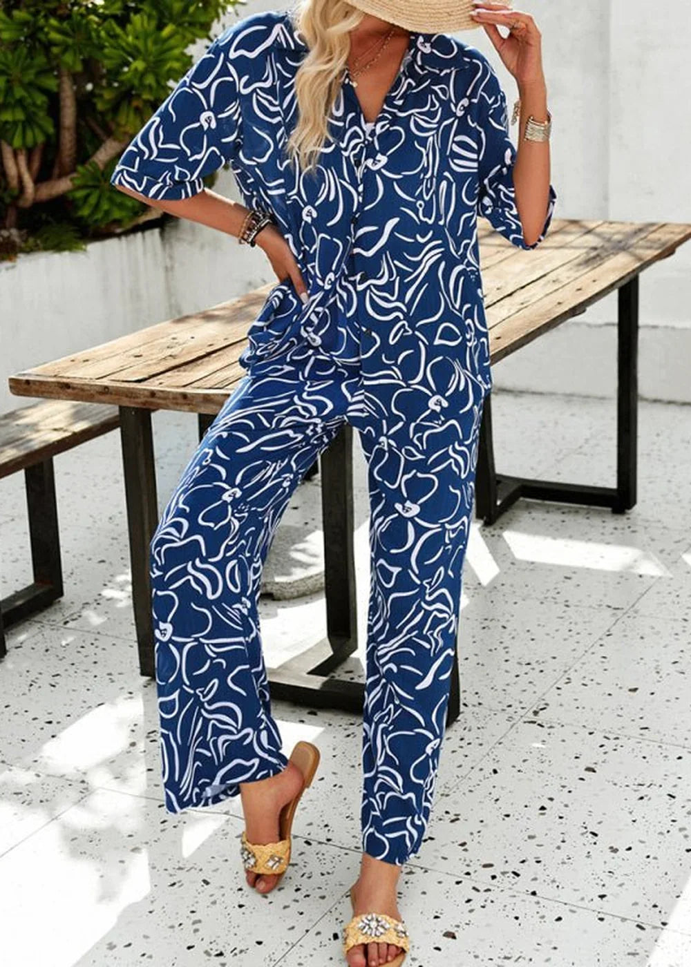 Navy blue and white abstract floral print wide-leg pant suit with short sleeves and collared neckline.