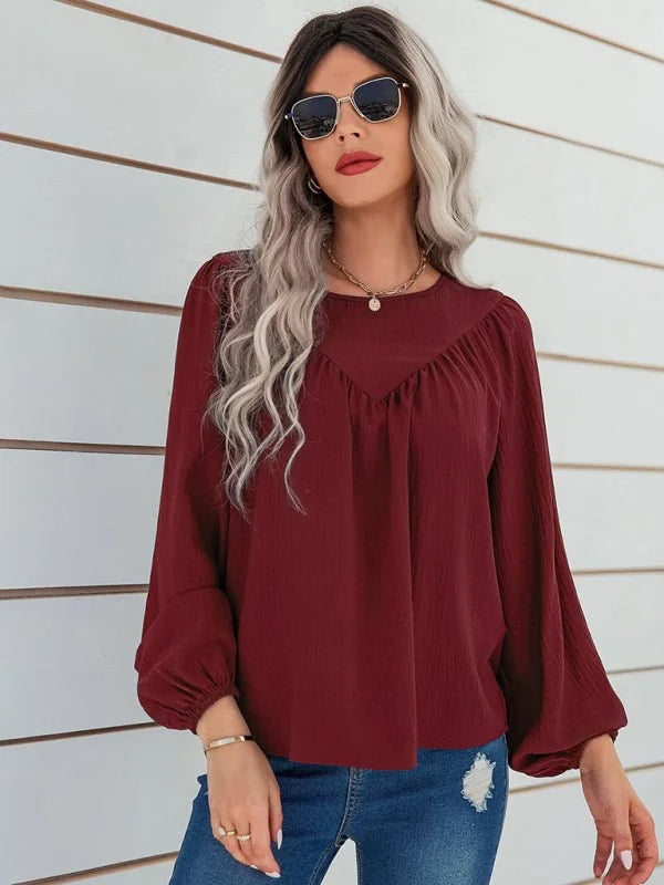 Burgundy textured peasant blouse with bishop sleeves on model.