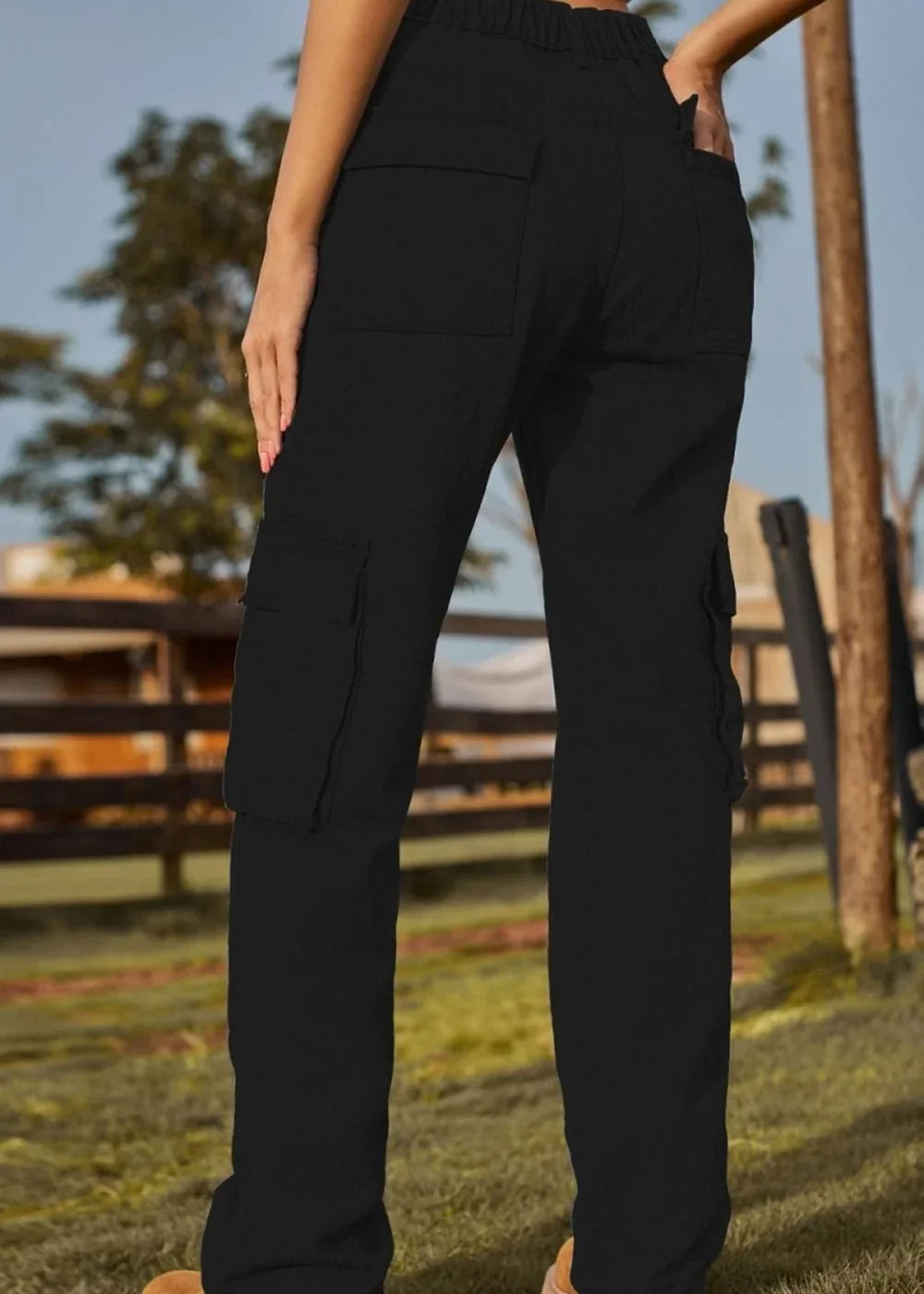 Black cargo pants with multiple pockets, shown from the back on a model outdoors.