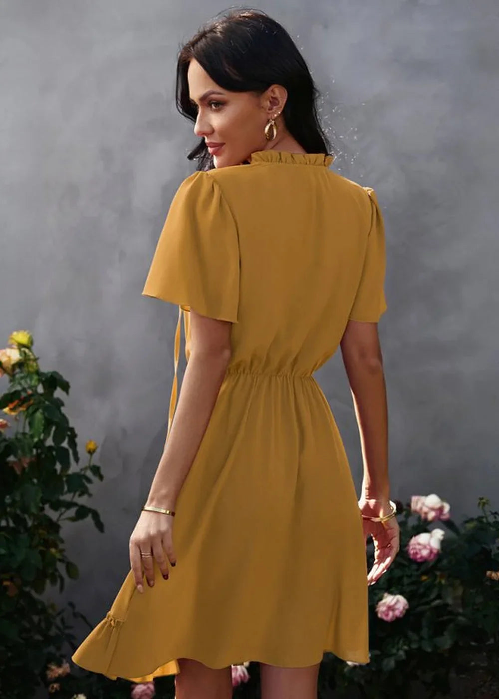 Golden yellow polyester dress with ruffled neckline and flutter sleeves, cinched waist, on model.