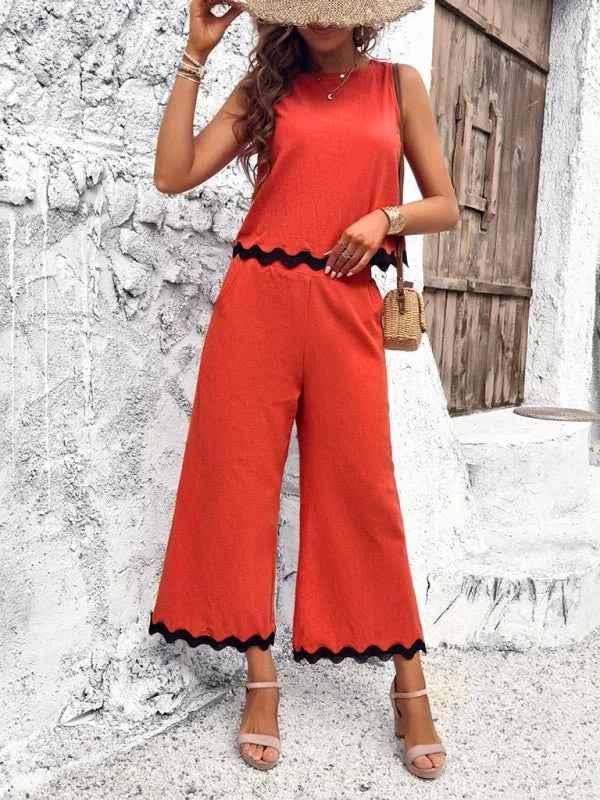 Orange wide-leg cropped pants with scalloped black trim and matching sleeveless top.