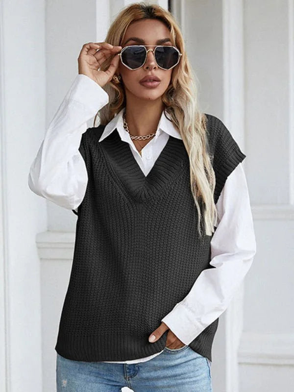 Woman wearing a black v-neck knit vest over a white collared shirt, with sunglasses on.