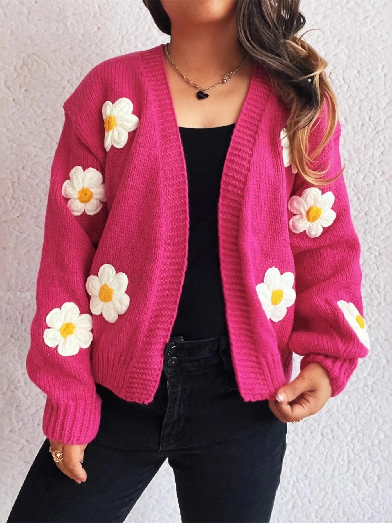 Hot pink knit cardigan with white and yellow daisy appliques, worn by a model.