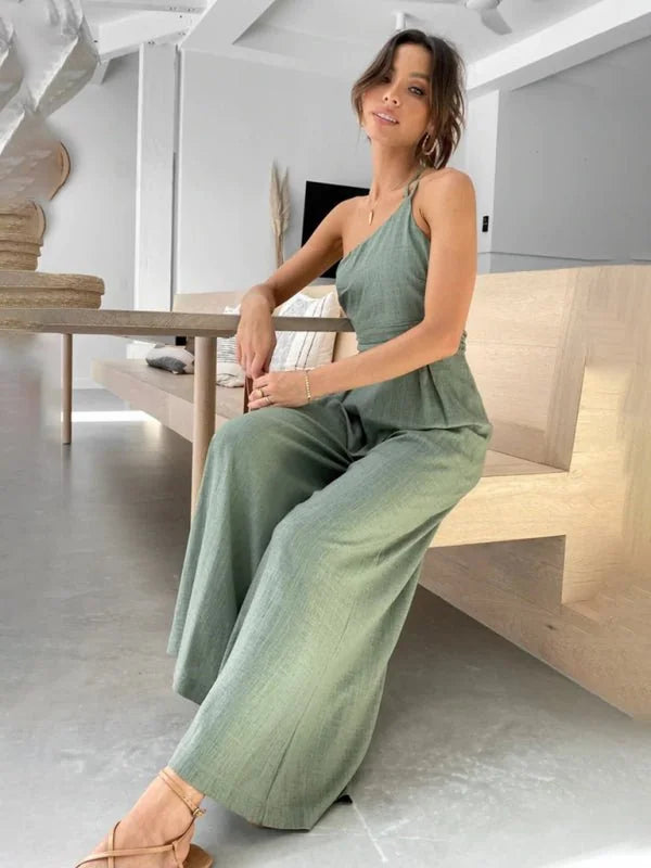 Sage green one-shoulder jumpsuit with wide legs, made of textured linen-like fabric, on a model.