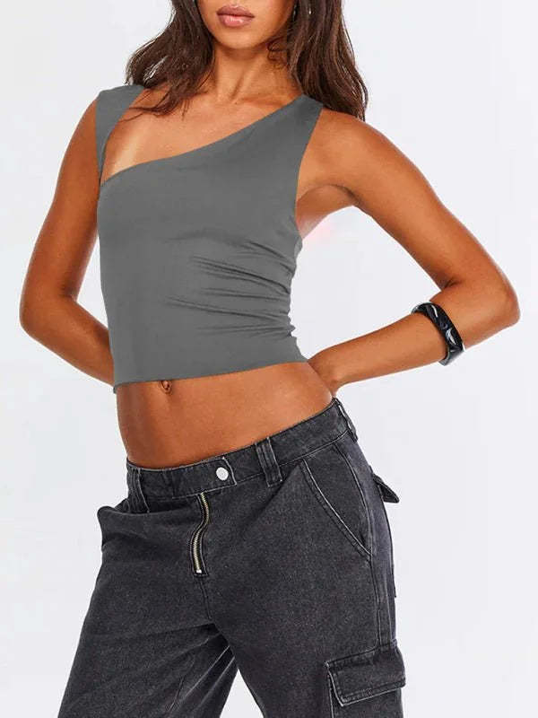 Close-up of a woman wearing a grey one-shoulder crop top and dark wash cargo pants.