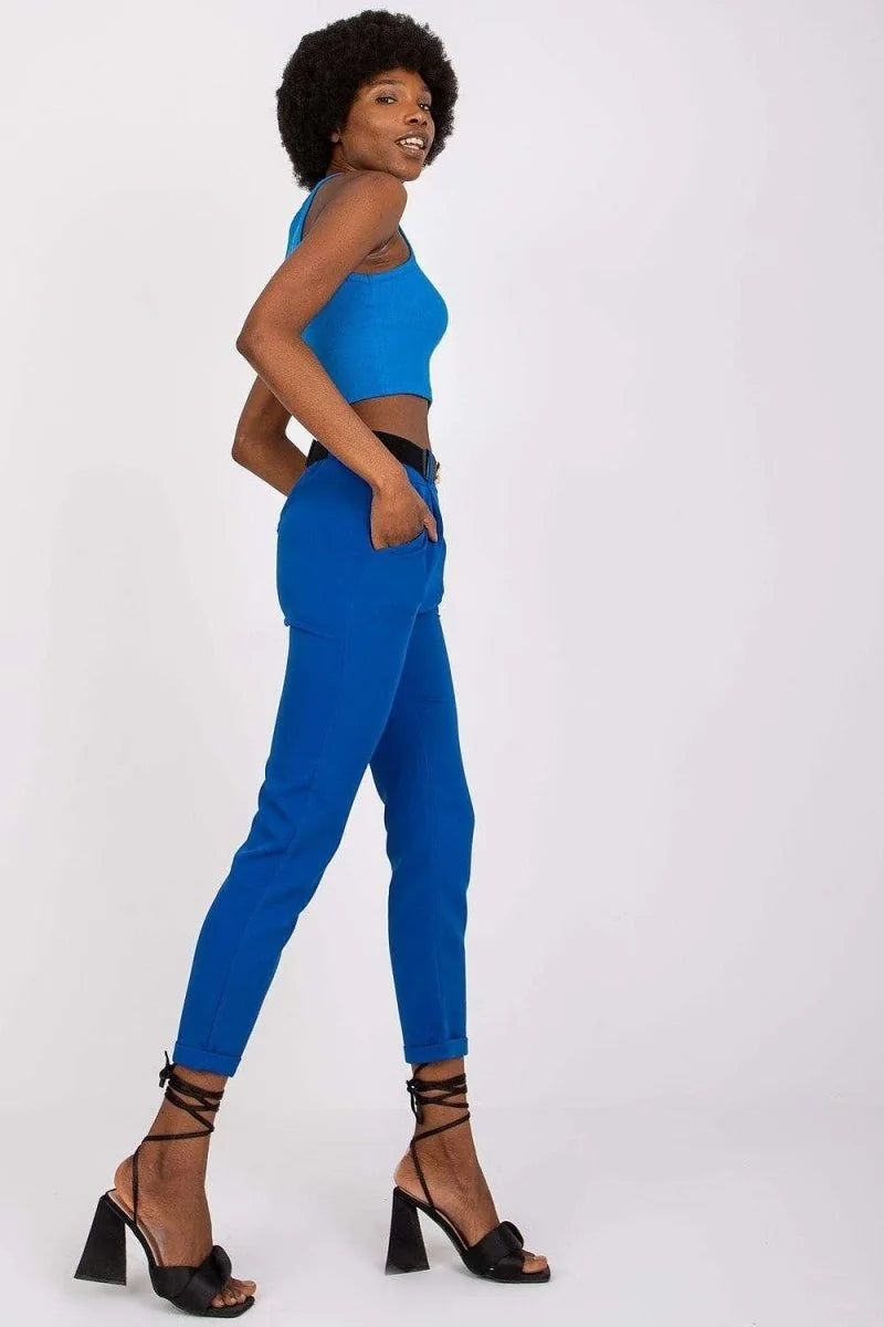 A woman in a blue crop top and matching blue pants with black strappy heels.