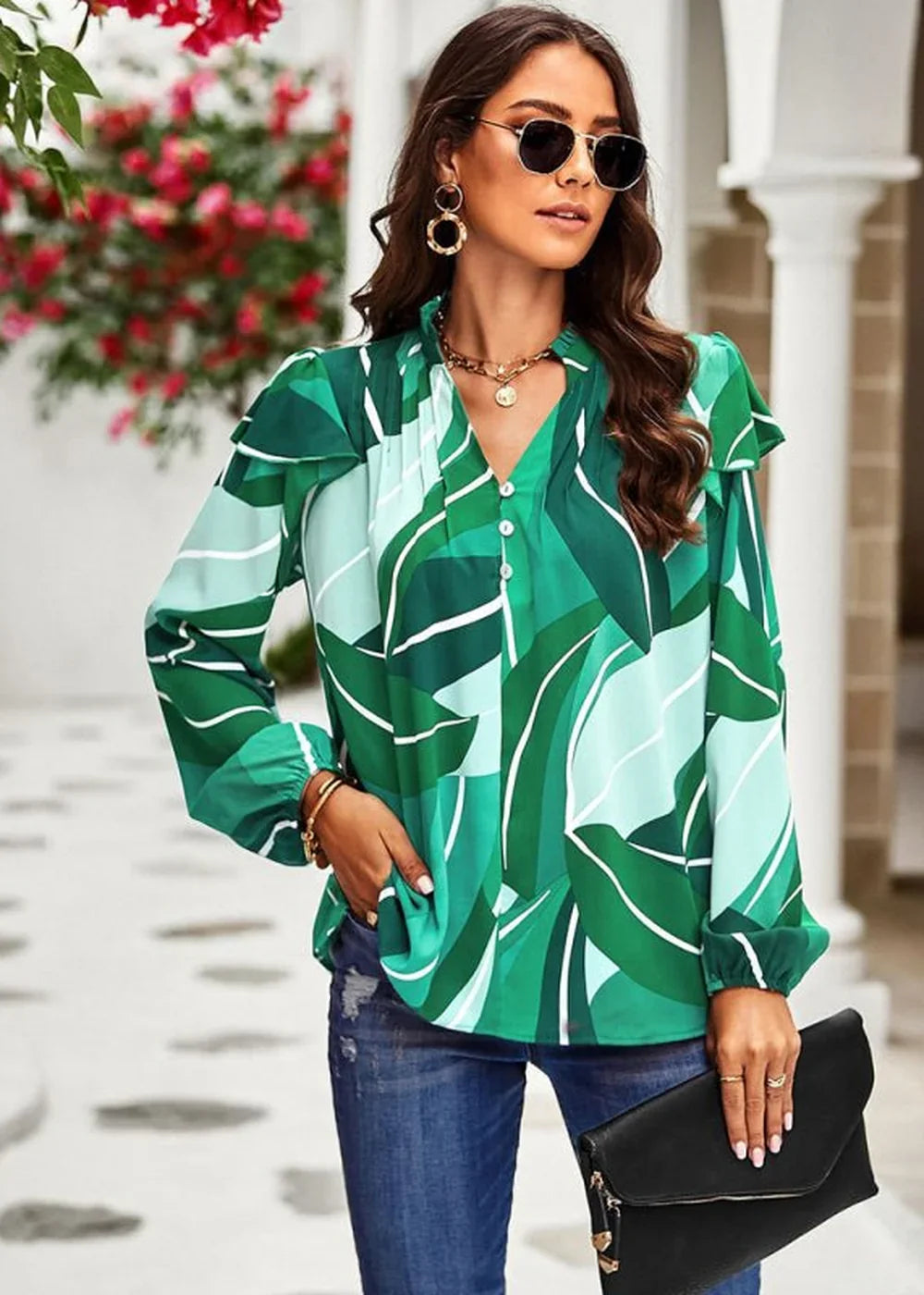 Green and light blue abstract leaf print blouse with ruffled sleeves and gold necklace on model.
