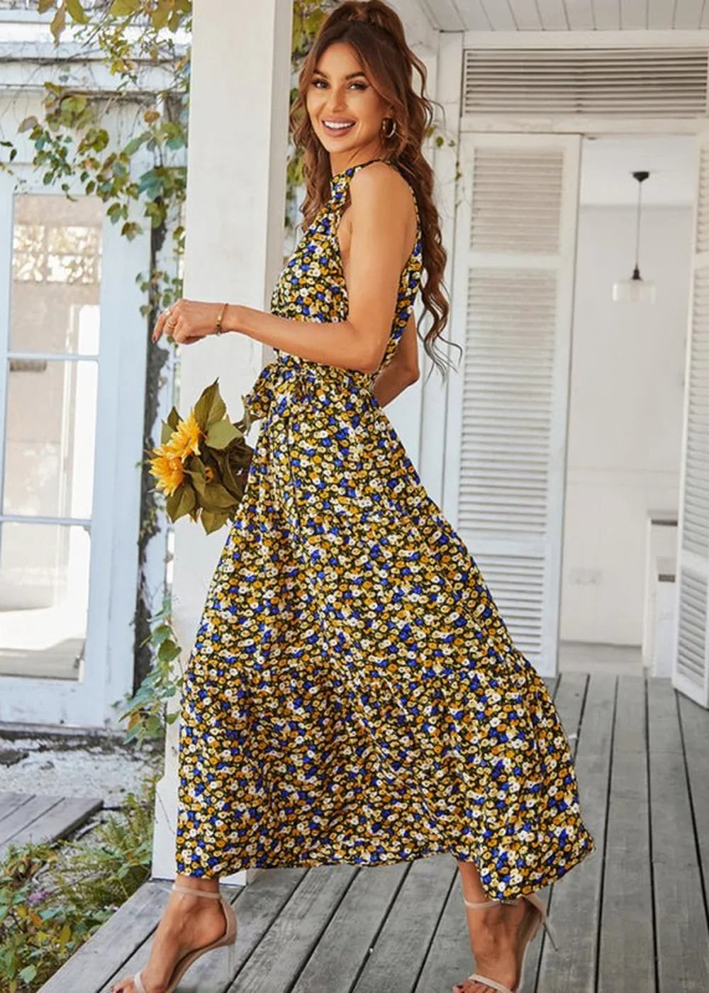 Yellow maxi dress with a blue and white floral print, sleeveless with a cinched waist and flowing skirt, on a model.