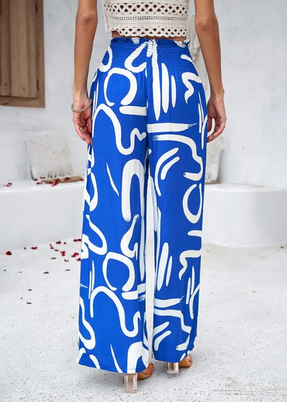 Blue wide-leg pants with a white abstract graphic print and smocked waist.
