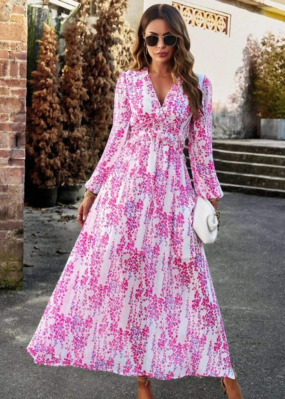 Long-sleeved white maxi dress with a vibrant pink and blue floral print, featuring a V-neck and flowing skirt.