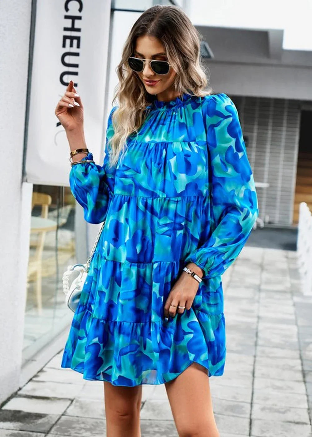 Blue and green floral print tiered dress with long sleeves and a mock neck, worn by a model.