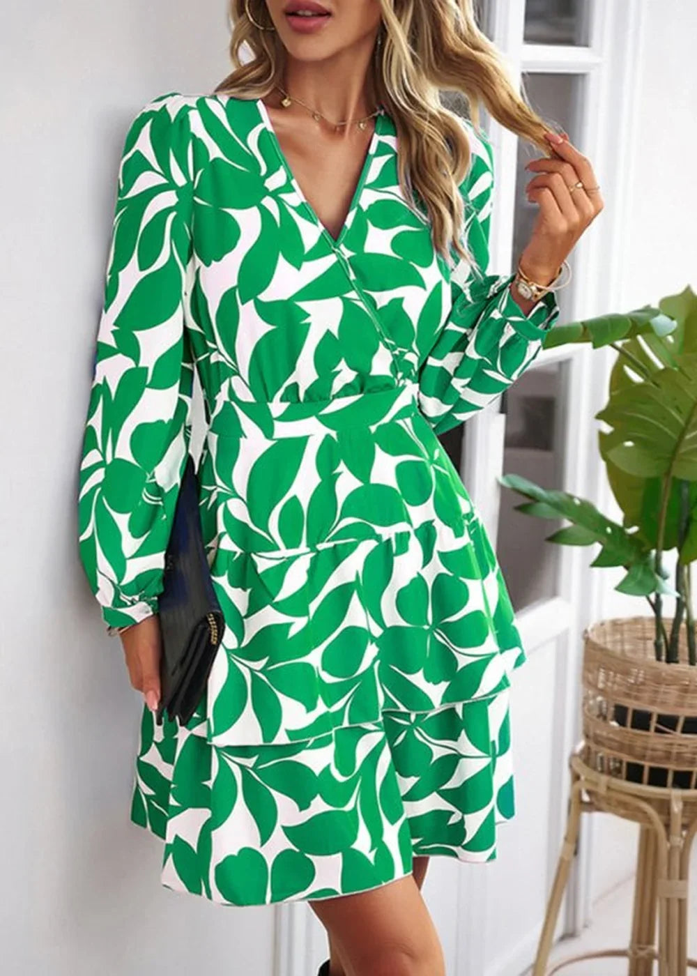 Green and white leaf print wrap dress with ruffled tiers and long sleeves.