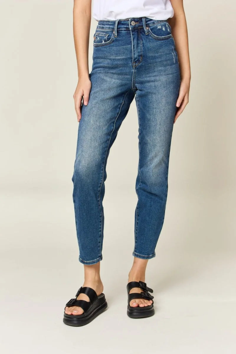 Medium wash distressed denim jeans with a high-waisted fit and ankle crop, shown on a model.