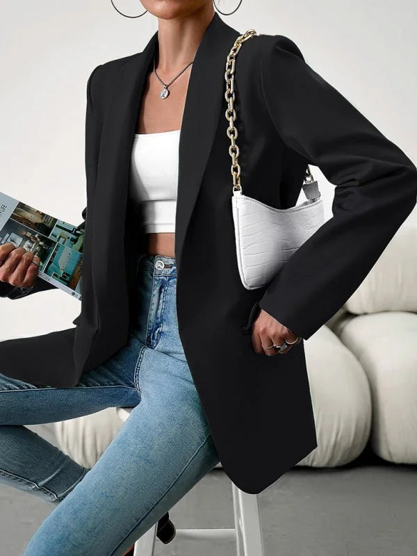 Black blazer with a white croc-embossed shoulder bag and light wash jeans.
