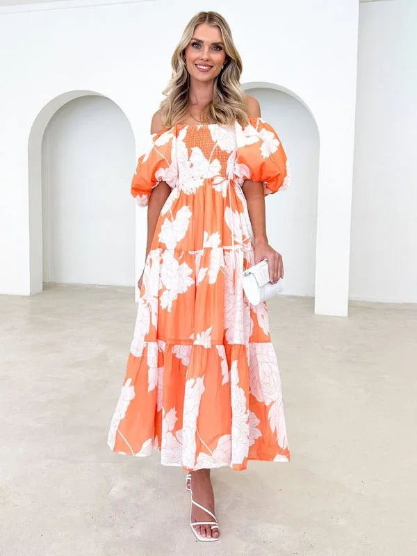 Orange off-the-shoulder maxi dress with white floral print and puff sleeves, worn by a model.