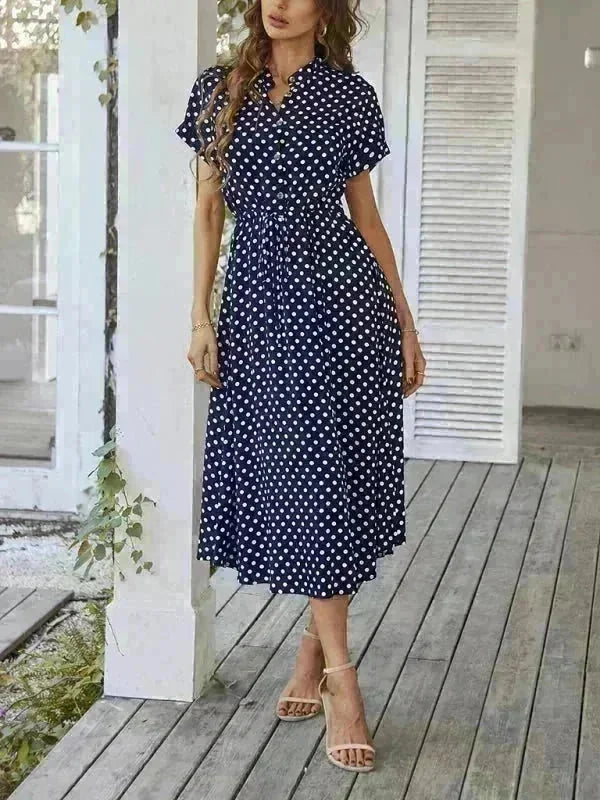 Navy blue rayon midi dress with white polka dots, cinched waist, and button-up front on a model.