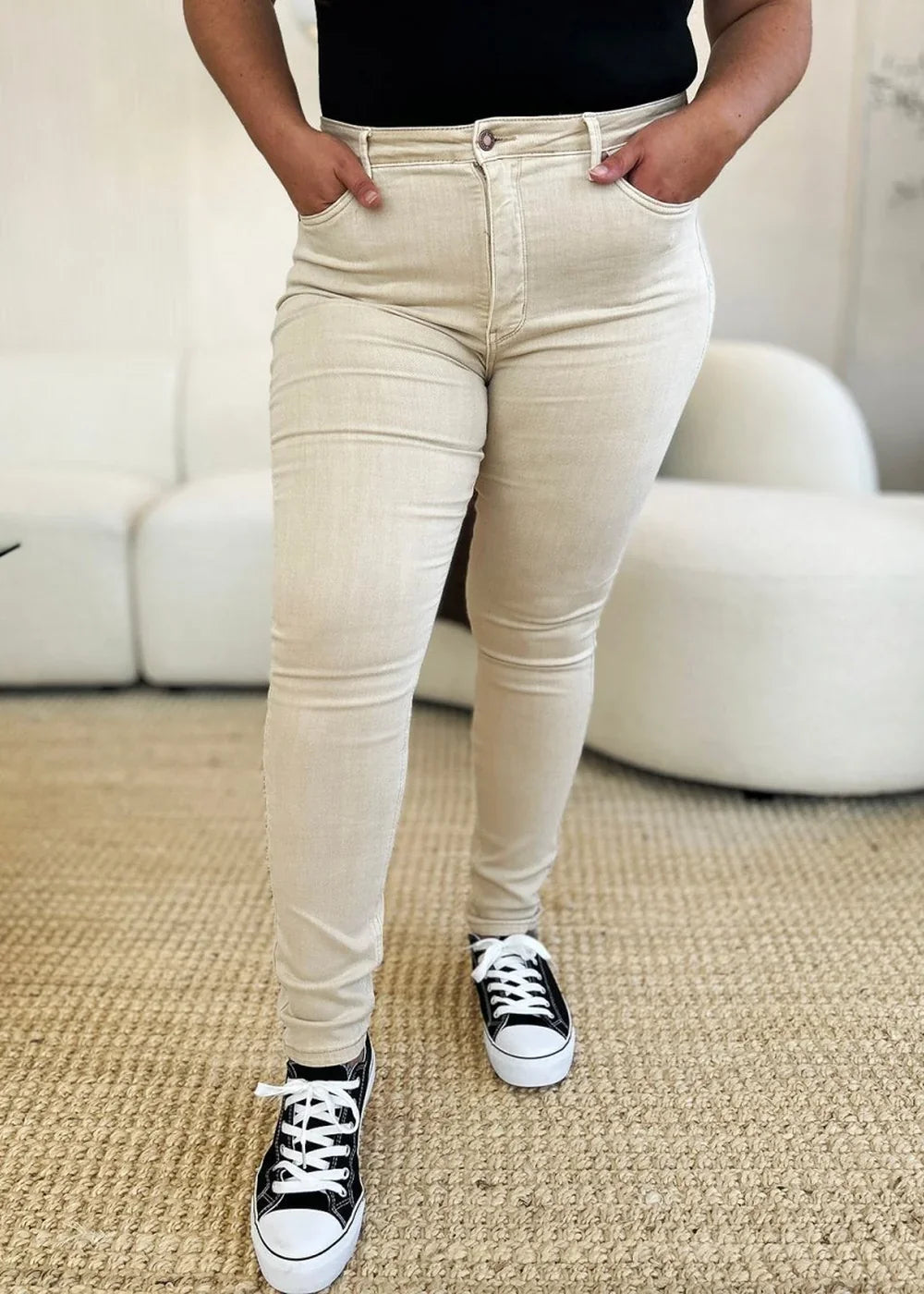 Light beige cotton blend skinny jeans with pockets and black canvas sneakers on model.