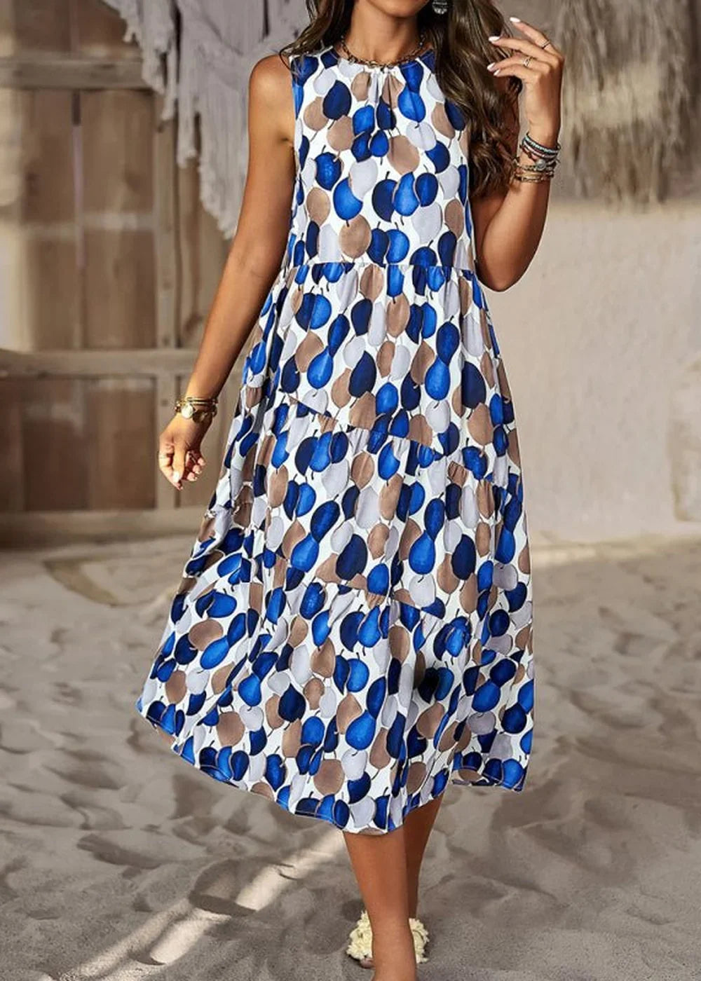 Sleeveless midi dress with a blue, brown, and white abstract leaf print, tiered skirt, on a model.