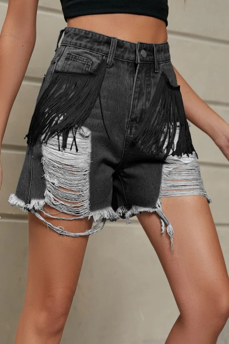 Dark wash denim shorts with black fringe, distressed rips, and frayed hem.