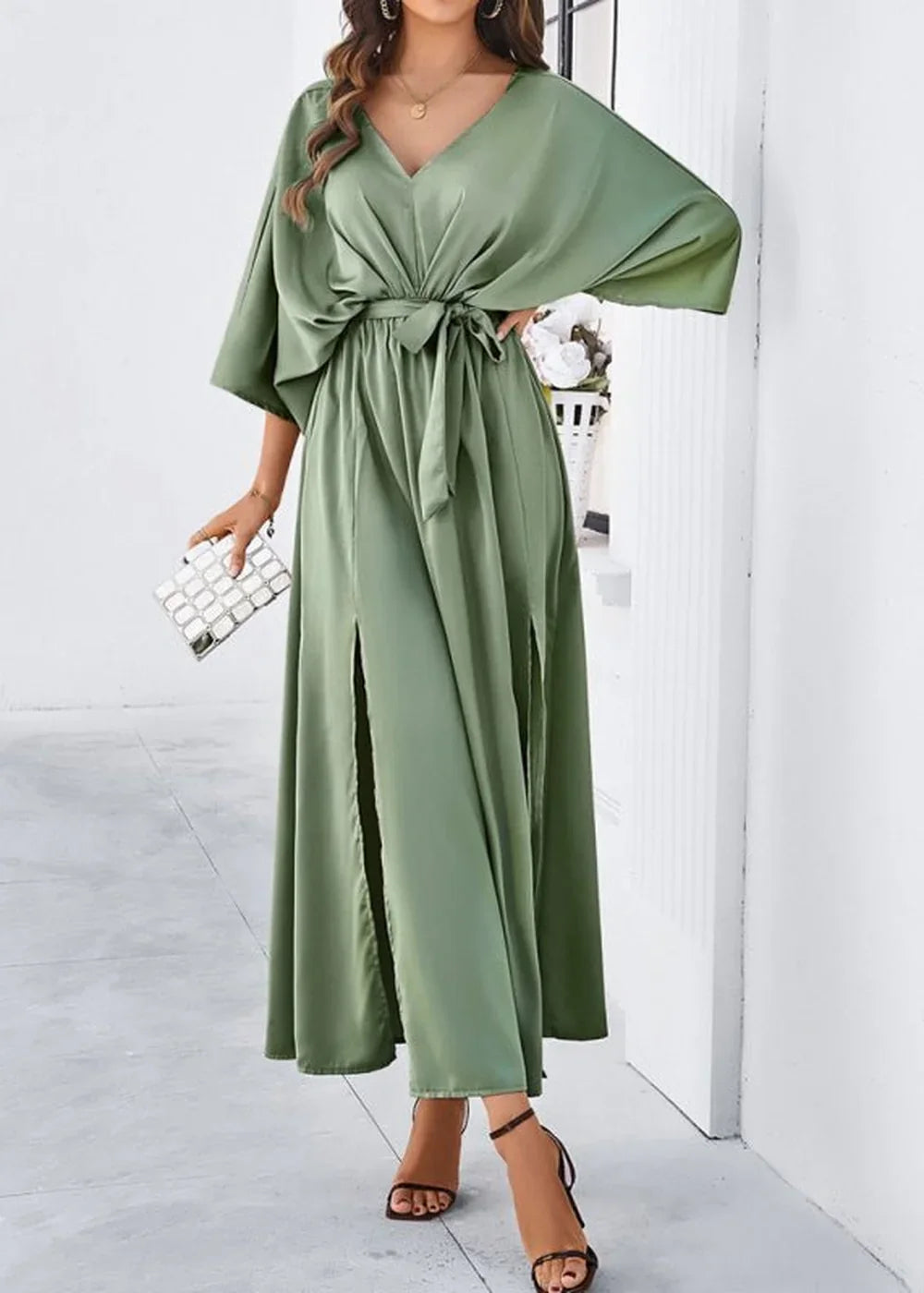 Sage green satin maxi dress with V-neck, tie waist, and thigh-high slits, worn by a model.