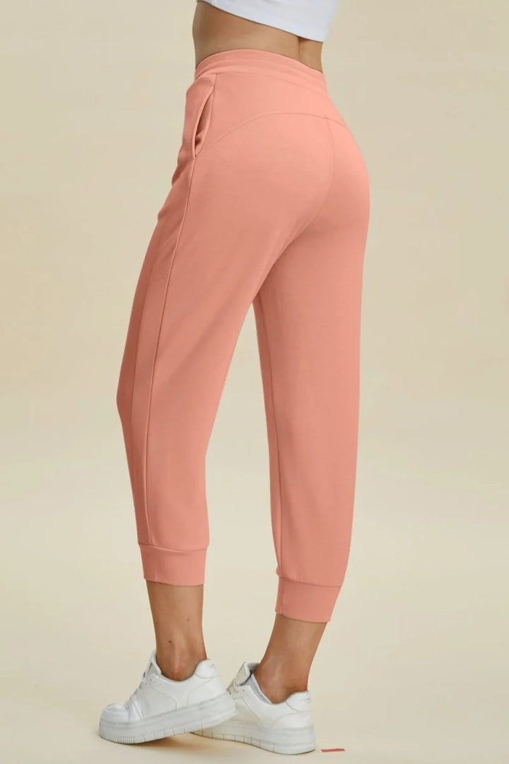 Coral cropped joggers with pockets and white sneakers, side view.